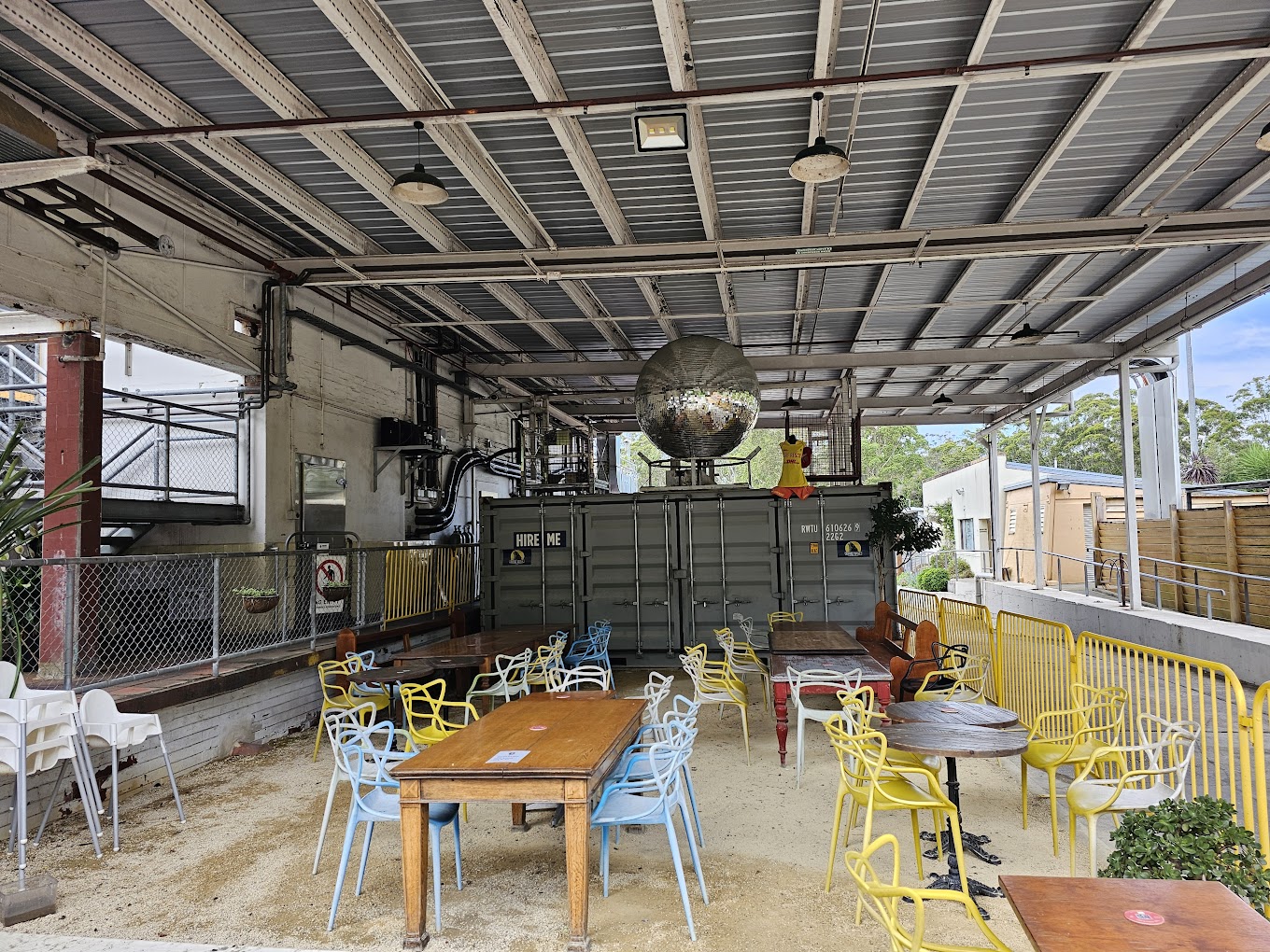 Industrial-style courtyard seating with a disco ball and shipping containers at Wyong Milk Factory