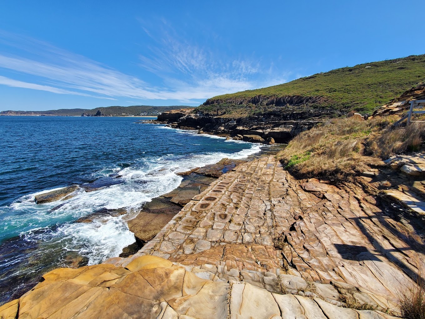 Sandstone-paved coastal track skirting cliffs and ocean waves in Bouddi National Park