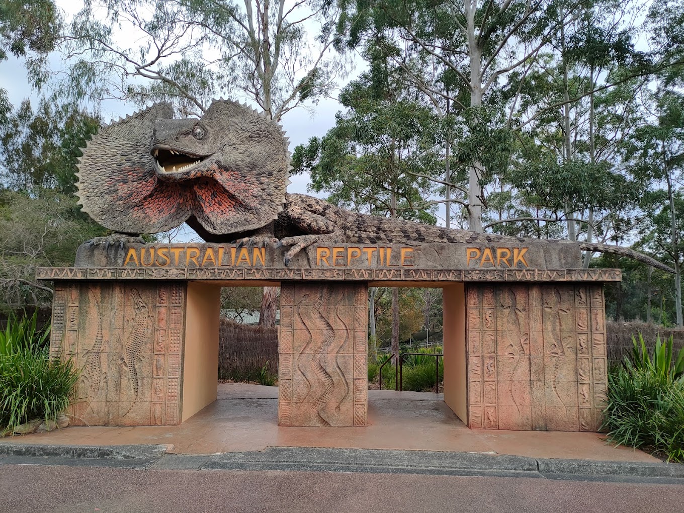 Entrance archway topped with a giant frilled-neck lizard sculpture at the Australian Reptile Park